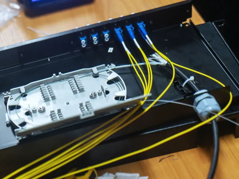 An open 1U rack termination box with a splice tray, blue LC duplex adapters and yellow pigtails